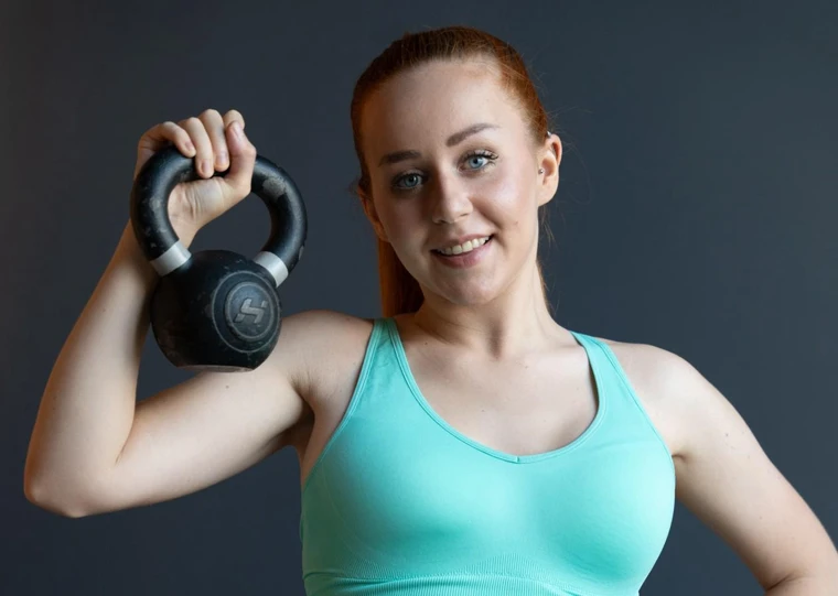 Michelle Emminger im türkisfarbenen Sporttop mit einer schwarzen Kettlebell